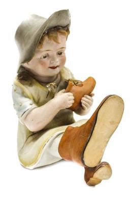 538 - FIGURA EN BISCUIT PRINCIPIOS DEL SIGLO XX. "NIÑO CON ZAPATO"